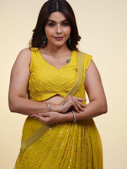 A close-up of the yellow pre-draped saree, focusing on the embellished blouse and the delicate draping of the fabric.