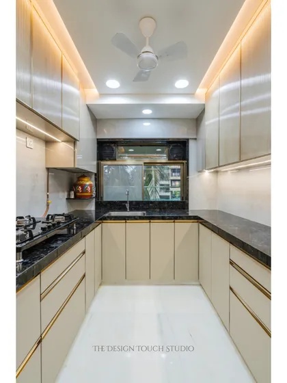 A full view of the U-shaped kitchen layout, which maximizes counter space and storage. The warm under-cabinet lighting and clean lines create a welcoming and efficient workspace.
