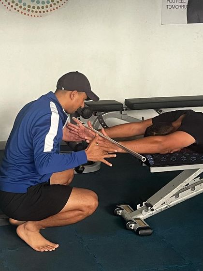 A physio guides an athlete through a specific stretching protocol. Individualized recovery and mobility work are just as important as strength training in our system.
