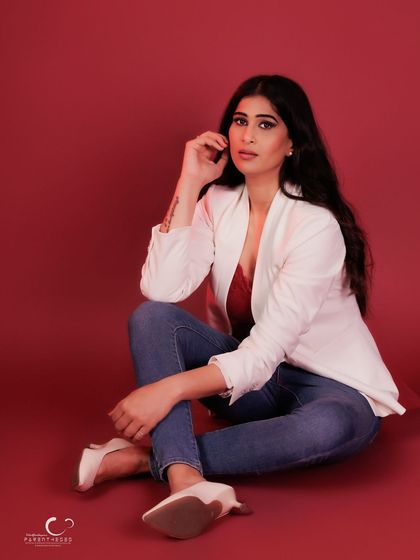 A confident and engaging seated portrait. Her direct gaze and relaxed pose invite the viewer into her world.