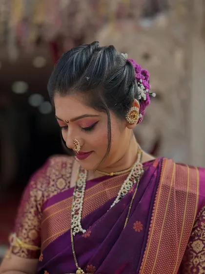 My client looking elegant in a purple Nauvari saree. Her look is completed with a simple hair bun adorned with flowers and traditional jewellery.