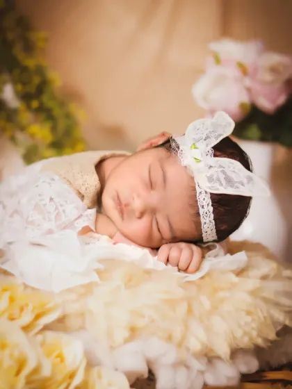 A detailed close-up from the floral teepee session, highlighting the baby's peaceful face and the delicate lace bow headband.