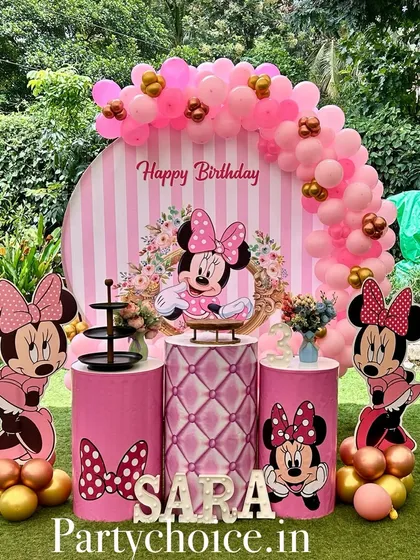 A lovely Minnie Mouse birthday setup in a garden. The outdoor setting adds a beautiful natural backdrop to the pink and gold decor.