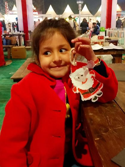 The happy and proud face of a young girl with the Santa ornament she created at our festive workshop.