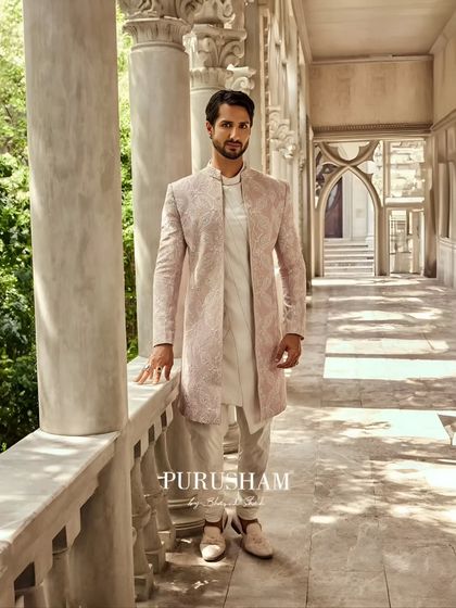 Standing in a corridor of history, this ensemble feels right at home. The long lines of the sherwani and the soft, elegant color are designed for the modern heir who appreciates both opulence and charm.