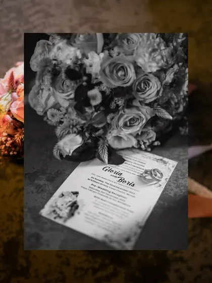 A classic black and white flat lay of the wedding rings placed on the invitation card, alongside the bride's beautiful bouquet.