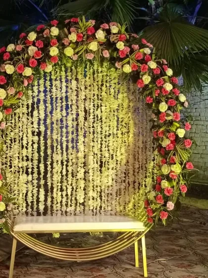 A beautiful semi-circular arch made with jasmine strings and a border of red and yellow roses. This makes for an elegant photo booth or seating backdrop for any wedding function.