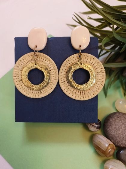 A clean product shot of the golden straw braided circle drop earrings.