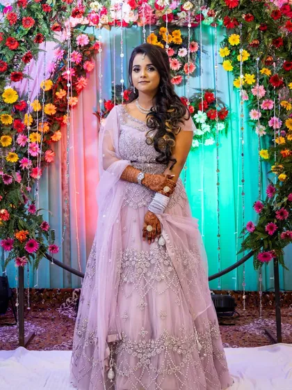 A full-length shot of the bride-to-be, standing against a colorful floral backdrop.