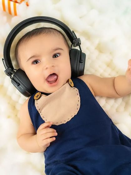 Rocking out in the clouds! A baby boy wears headphones and looks like he's singing along to his favorite song.