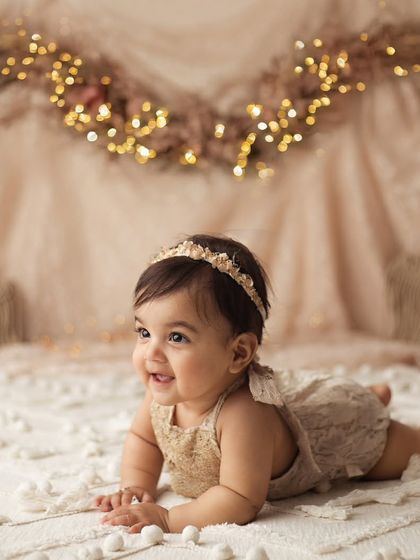 A real-life doll. Her squishy cheeks and big, sparkling eyes are just everything in this cozy, fairy-lit boho setup.