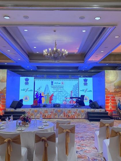 The elegant ballroom setup for the BMRCL Cultural Event at the Taj West End. We transformed the venue with custom stage backdrops, round table seating with classic covers, and sophisticated lighting.