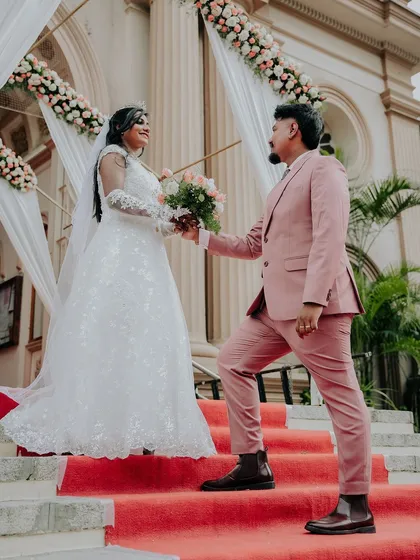 The groom presents the bouquet to his bride on the church steps, a modern fairy tale moment.