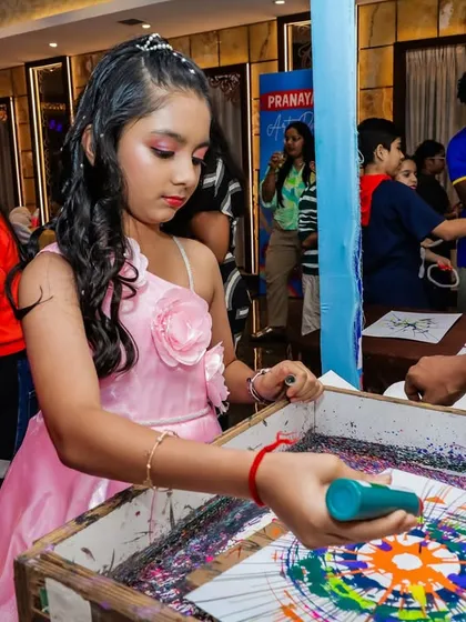 A girl creates a vibrant design at the spin art station during an "Art Attack" themed party. The results are always unique and impressive.