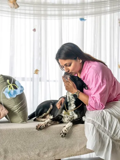 An intimate moment from a Mother's Day session. A woman in a pink shirt gives her black and white spotted dog a gentle kiss, showcasing the quiet love they share.