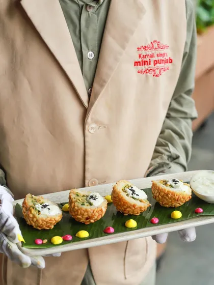 A server presents our Rice Paper Puffs topped with Citrus Tatami Veggies. This dish offers a delightful fusion of crunchy textures and fresh, zesty flavours.