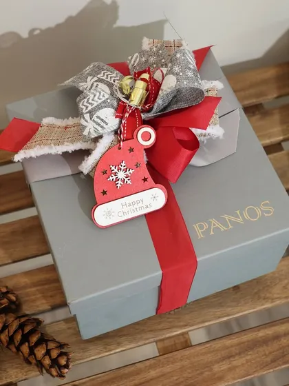 Even a simple gift box is an opportunity for beauty. Here, a Christmas-themed gift is topped with a festive tag and a charming, rustic bow, showing our attention to detail for every occasion.