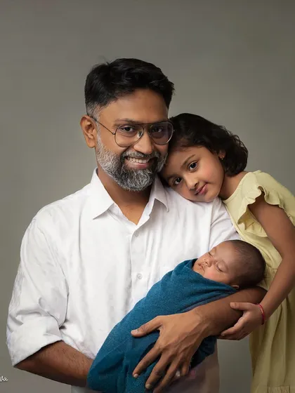 A father's gentle love. This portrait shows a dad with his two children, his newborn son sleeping peacefully in his arms while his daughter rests her head on his shoulder.