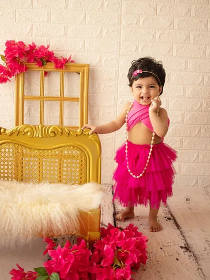 A confident birthday girl stands by her golden chaise, ready to celebrate her big day.