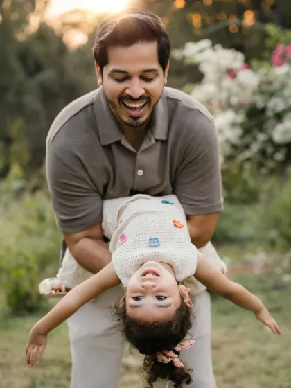 A father playfully holds his daughter upside down in a park. These fun, action-filled shots are a great way to capture a child's personality.