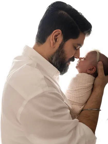 A father and his newborn baby share a sweet nose-to-nose moment. The connection is palpable.