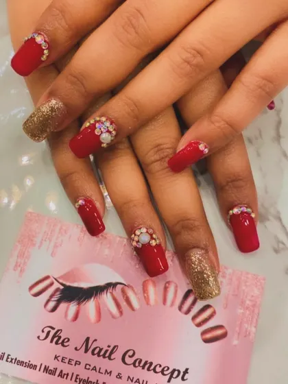 A classic party look with bold red square nails and gold glitter accent nails. The red nails are further embellished with clusters of opulent crystals at the cuticle for a rich, festive feel.