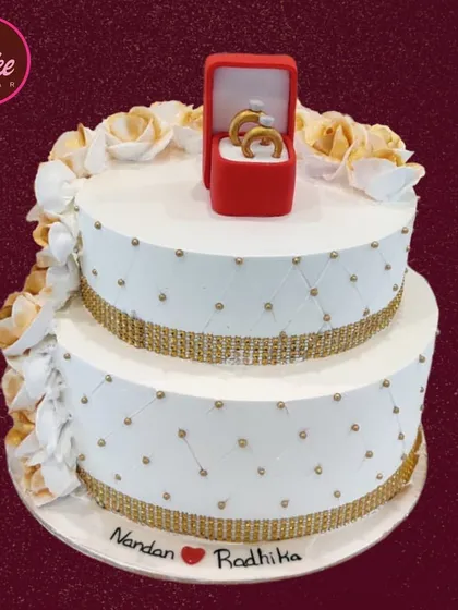 For a truly memorable engagement, I designed this two-tier cake featuring an edible, handcrafted ring box. It’s a unique and sweet way to celebrate the beginning of your journey together, combining elegant design with a personal touch.