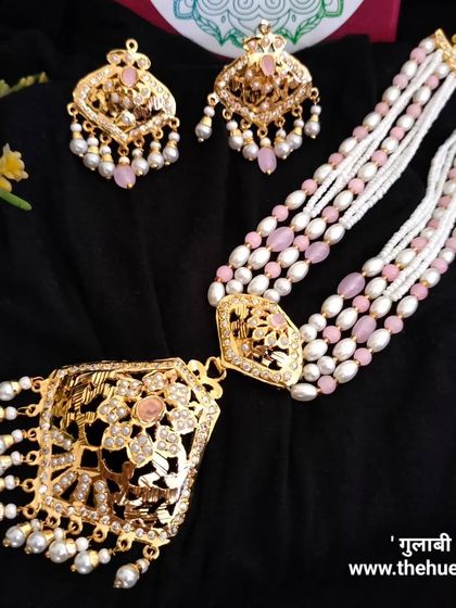 The 'गुलाबी' (Gulabi) necklace set, featuring a long pendant and strands of pink and white pearls. This piece has a soft, feminine charm perfect for daytime events.