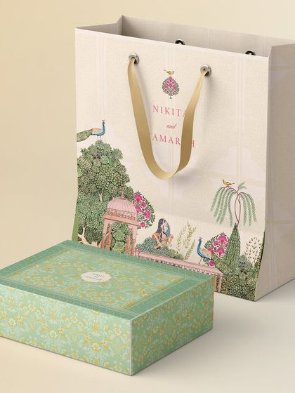 The custom-designed gift bag and box for the Jaipur wedding. The artwork from the invitations was extended to the packaging, featuring a beautiful scene with a peacock and traditional architecture, creating a cohesive gifting experience.