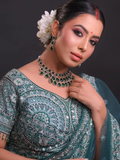 This Bengali-inspired bridal look features a prominent red bindi and beautifully defined eyes. The hair is styled in a traditional bun adorned with fresh flowers, a technique we cover in detail.