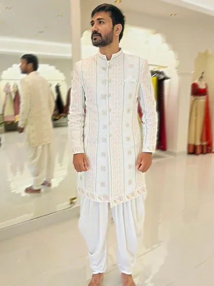 This timeless white Chikankari sherwani is paired with classic dhoti pants. It's a perfect blend of traditional craftsmanship and modern tailoring for the sophisticated Indian man.