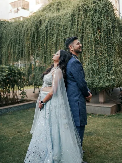 A creative back-to-back pose in a beautiful garden setting. This engagement portrait is both stylish and symbolic of their supportive partnership.