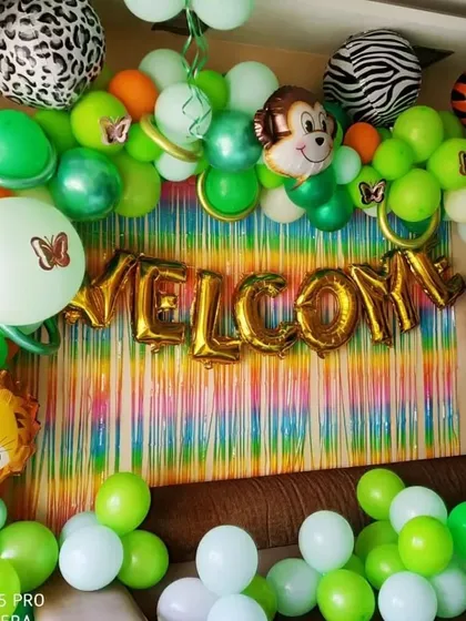 Welcome to the jungle. This vibrant jungle-themed decor is perfect for a fun baby shower, with green and orange balloons, animal print accents, and foil balloons shaped like a monkey, tiger, and lion.