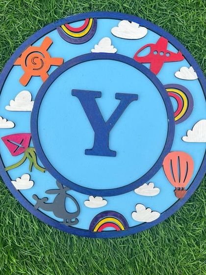 This travel-themed monogram is one of our new DIY painting activities. It's a wonderful way to create a personalized piece of decor for a child's room, featuring fun elements like airplanes, hot air balloons, and clouds.