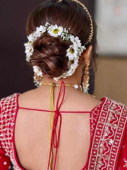 A beautiful bridal bun adorned with a gajra of fresh white daisies. This is a classic and elegant choice that never goes out of style.