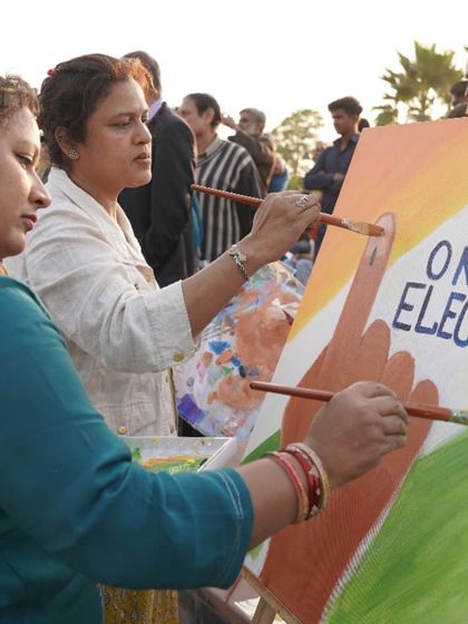 Two of our artists collaborate on a canvas during the 'One Nation, One Election' live painting event. Community art projects are a wonderful way to spread important messages.