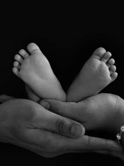 A beautiful black and white shot of a newborn's feet resting in their parent's hands. They won't be this little forever.