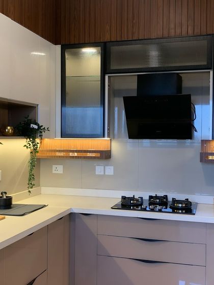 This kitchen showcases a vibrant color combination with handleless cabinets and fluted glass shutters. The design includes a dedicated space for the chimney, ensuring a clean and modern look.