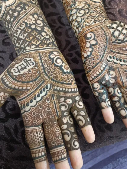 A close-up of the palm where the name 'Yash' is subtly integrated into the intricate patterns of this bridal design.