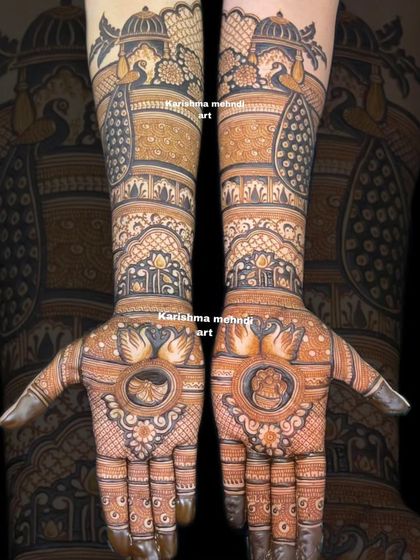 This bridal henna design showcases swans and a Ganesha figure on the palms, symbolizing grace and new beginnings. The forearms are decorated with palace and peacock motifs for a classic touch.