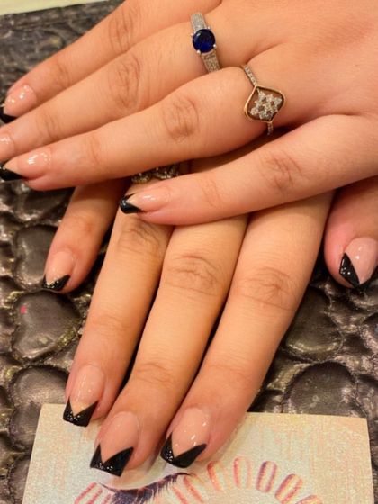 A short and edgy version of the V-shaped French manicure. This set features a nude base with black glitter V-tips on square nails.