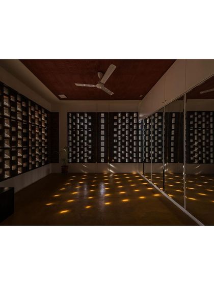 A dance room where the walls are made of perforated brick jaalis. As the sun moves, a grid of light spots travels across the floor, creating a magical and inspiring atmosphere for movement.