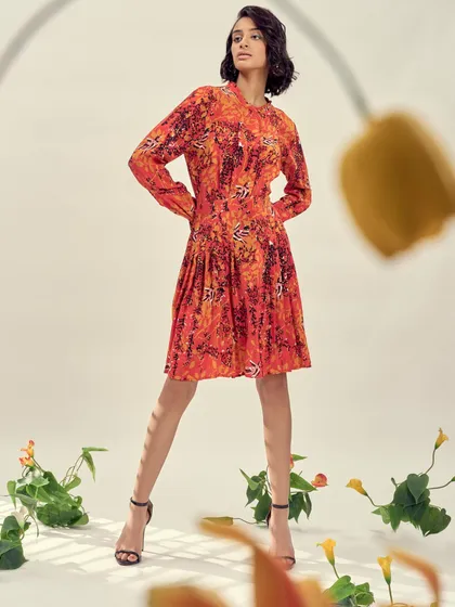 A vibrant orange printed dress styled for a brand campaign. The focus was on creating a playful yet sophisticated look with floral props and dynamic posing.