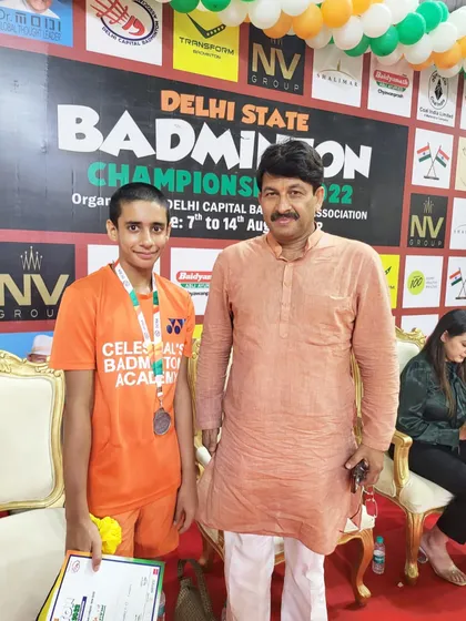 Our player Aryan Negi standing with a dignitary after securing a silver medal in the Mixed Doubles U-15 category at the Delhi State Badminton tournament, showcasing his competitive success.