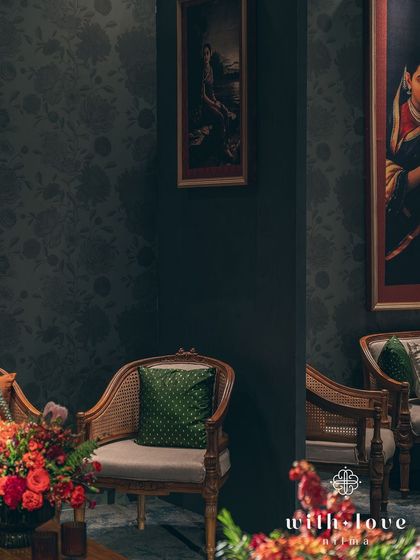 A quiet seating corner with classic furniture and a green accent cushion, set against a backdrop of timeless art.
