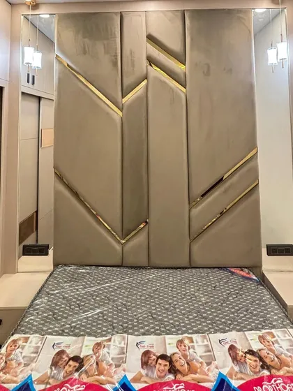 A close-up of a luxurious, custom-designed headboard. The geometric pattern with beige upholstery and gold metallic inserts creates a highly modern and glamorous statement piece for a master bedroom.