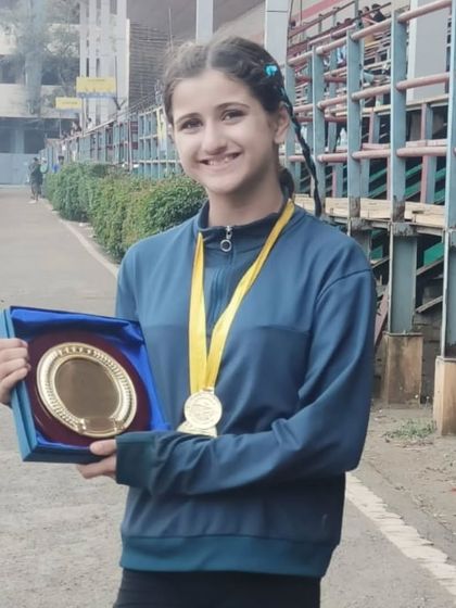 Linn proudly holding her awards. Her incredible performance is an inspiration to all our young athletes.