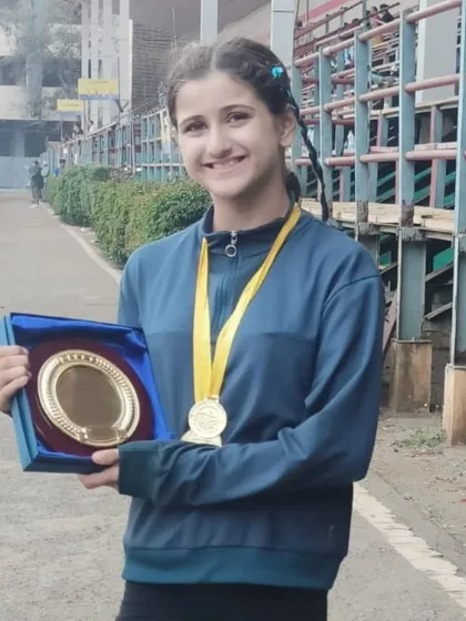 Linn proudly holding her awards. Her incredible performance is an inspiration to all our young athletes.