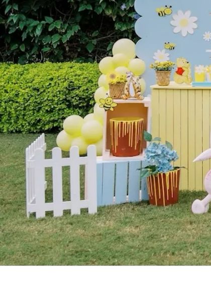 A corner of the Hundred Acre Wood, featuring a white picket fence, 'hunny' pots, and a Piglet cutout, creating a sweet and picturesque scene.
