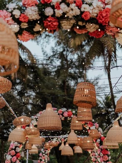 A close-up of the boho-chic decor for a Goa wedding, featuring woven lampshades and a lush floral arch.